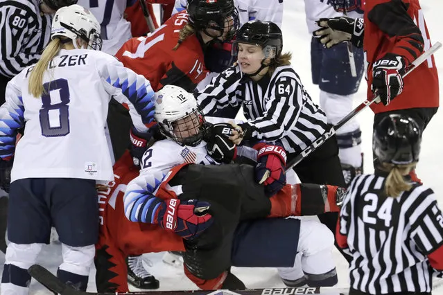 Official Jenni Heikkinen (64), of Finland, tries to separate Kelly Pannek (12), of the United States, and Laura Stacey (7), of Canada, as they scuffle during the third period of a preliminary round during a women's hockey game at the 2018 Winter Olympics in Gangneung, South Korea, Thursday, February 15, 2018. Canada won 2-1. (Photo by Julio Cortez/AP Photo)