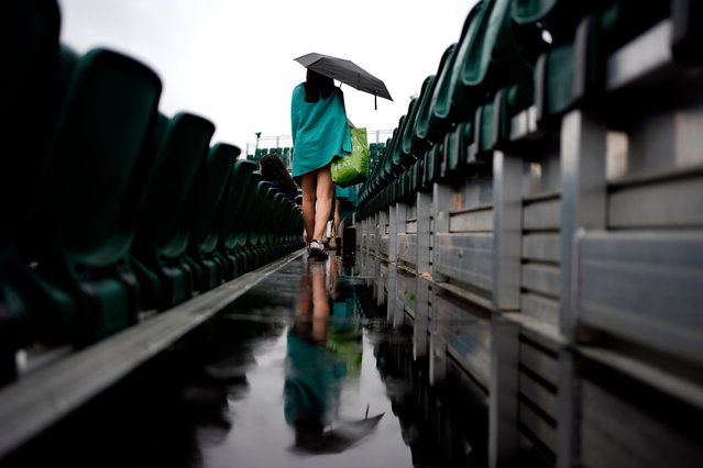 A spectator shelters from the rain on day three of the 2025 Wimbledon Championships at the All England Lawn Tennis and Croquet Club, London on Wednesday, July 2, 2025. (Photo by Jordan Pettitt/PA Images via Getty Images)