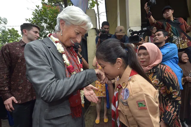 Managing Director of the International Monetary Fund (IMF) Christine Lagarde (L) is greeted by an Indonesian schoolgirl (R) during a visit in Cilincing, Jakarta on February 28, 2018. Lagarde visited Jakarta for a high- level international conference and preparations for the annual meetings of the IMF and World Bank Group which will be held in Nusa Dua, Bali in October. (Photo by Adek Berry/AFP Photo)
