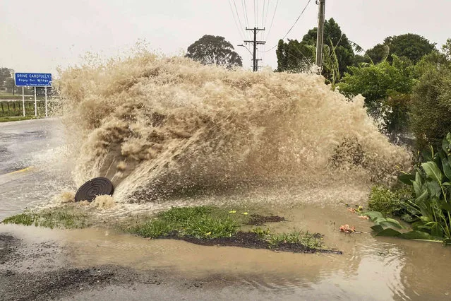 Water gushes from a storm drain access port on a street in Te Awanga, southeast of Auckland, New Zealand, Tuesday, February 14, 2023. The New Zealand government declared a state of emergency across the country's North Island, which has been battered by Cyclone Gabrielle. (Photo by Warren Buckland/Hawkes Bay Today via AP Photo)