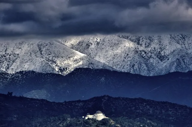 Storm clouds and snow are seen over the San Gabriel mountain range behind Griffith Observatory in the Hollywood Hills part of Los Angeles on Sunday, February 26, 2023. A powerful winter storm that swept the West Coast with flooding and frigid temperatures has shifted to southern California, swelling rivers to dangerous levels and dropping snow in even low-lying areas around Los Angeles. (Photo by Richard Vogel/AP Photo)