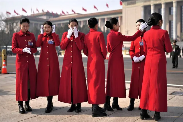 Bus hostesses adjusts their hair before photos outside the Great Hall of the People the eve of the opening session of the annual meeting of China's National People's Congress (NPC) in Beijing, Saturday, March 4, 2023. (Photo by Ng Han Guan/AP Photo)