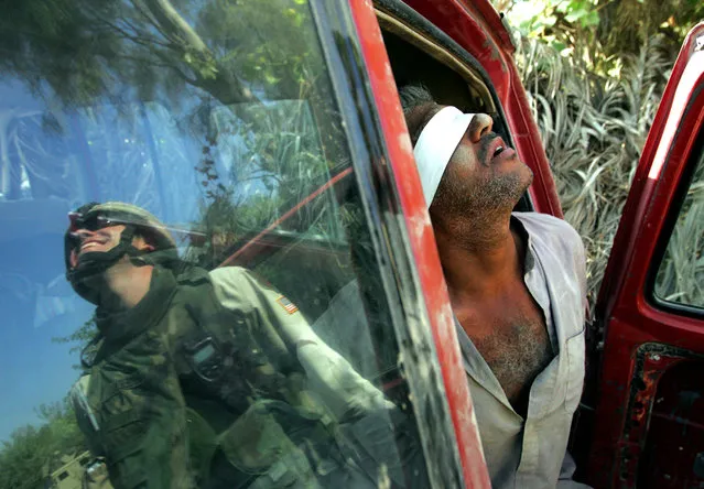 An Iraqi man suspected of having explosives in his car is held after being arrested by the U.S army near Baquba, Iraq, October 15, 2005. (Photo by Jorge Silva/Reuters)