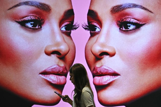 A woman walks past a cosmetic advertisement in Phoenix Mall of Asia in Bengaluru on September 19, 2025. (Photo by Idrees Mohammed/AFP Photo)