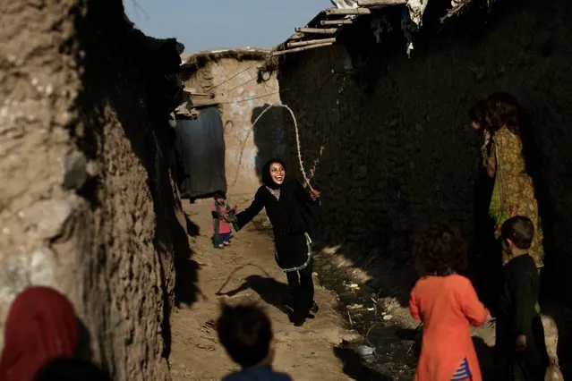 Pakistani children, who were displaced with their families from Pakistan's tribal areas due to fighting between militants and the army, watch a girl skipping a rope, while playing in an alley of a poor neighborhood on the outskirts of Islamabad, on January 28, 2013. (Photo by Muhammed Muheisen/AP Photo)