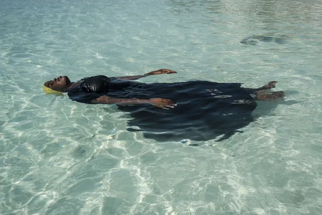 Finding Freedom in the Water: A young woman learns to float, in the Indian Ocean, off Nungwi, Zanzibar, November 24, 2016. Traditionally, girls in the Zanzibar Archipelago are discouraged from learning how to swim, largely because of the strictures of a conservative Islamic culture and the absence of modest swimwear. But in villages on the northern tip of Zanzibar, the Panje Project (panje translates as ‘big fish’) is providing opportunities for local women and girls to learn swimming skills in full-length swimsuits, so that they can enter the water without compromising their cultural or religious beliefs. (Photo by Anna Boyiazis/World Press Photo)