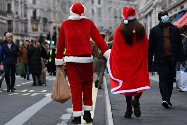 Santas walk among the crowds of shoppers on the newly pedestrianized Regent Street in London on December 12, 2020, as with under two weeks to Christmas, people take advantage of the easing of England's restrictions on shop openings to combat the spread of the novel coronavirus. (Photo by Justin Tallis/AFP Photo)