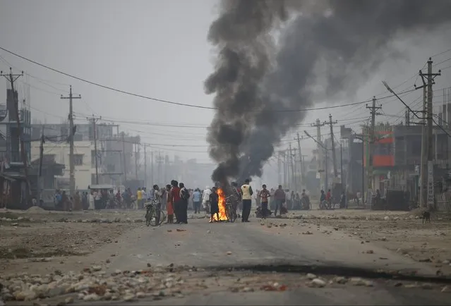 Protesters stand near burning tyres as they gather to block the highway connecting Nepal and India, during a general strike called by Madhesi protesters demonstrating against the new constitution in Birgunj, Nepal November 5, 2015. (Photo by Navesh Chitrakar/Reuters)