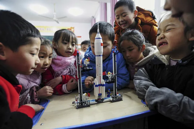 Children look at a model of the Longmarch rocket during an aerospace education lesson at a primary school in Yunyang county in southwestern China's Chongqing on December 16, 2020. (Photo by AFP Photo/China Stringer Network)