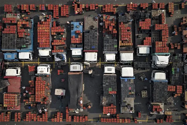 Seen from above, vendors sell tomates from their trucks at Lo Valledor central wholesale produce market in Santiago, Chile, Thursday, February 9, 2023. (Photo by Matias Delacroix/AP Photo)