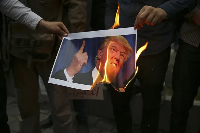 Iranian demonstrators burn a picture of the U.S. President Donald Trump during  during a protest in front of the former U.S. Embassy in response to President Donald Trump's decision Tuesday to pull out of the nuclear deal and renew sanctions, in Tehran, Iran, Wednesday, May 9, 2018. (Photo by Vahid Salemi/AP Photo)