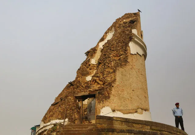 A Nepalese policeman stands guard next to the Dharahara tower which collapsed in the 2015 earthquake, during a function to mark the third anniversary of the earthquake in Kathmandu, Nepal, Wednesday, April 25, 2018. The violence of the 7.8-magnitude earthquake  killed nearly 9,000 people and left countless towns and villages across central Nepal in shambles. (Photo by Niranjan Shrestha/AP Photo)
