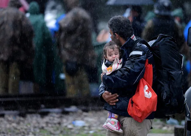 A migrant father holds his child after after crossing the border near Gevgelija, The Former Yugoslav Republic of Macedonia, 27 November 2015. Several hundreds of mostly Iranians have been blocking the border line between Greece and Macedonia for the last four days. Macedonia, Serbia and Croatia had started restricting access to migrants on the Balkan route to Syrians, Iraqis and Afghans. (Photo by Nake Batev/EPA)