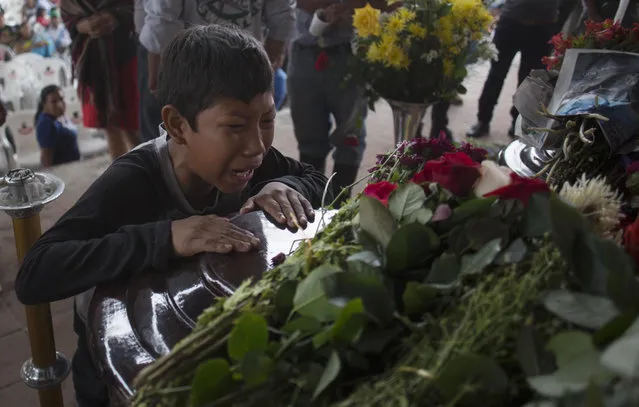 A youth cries over the coffin of Nery Otoniel Gomez Rivas, 17, whose body was pulled from the volcanic ash during the eruption of the Volcan de Fuego, which in Spanish means Volcano of Fire, during his wake at the main park of the town San Juan Alotenango, Guatemala, Monday, June 4, 2018. A fiery volcanic eruption in south-central Guatemala sent lava flowing into rural communities, killing dozens as rescuers struggled to reach people where homes and roads were charred and blanketed with ash. (Photo by Luis Soto/AP Photo)