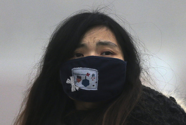 In this December 1, 2015 photo, a woman wears a mask to protect herself from pollutants near Tiananmen Gate on a heavily polluted day in Beijing. (Photo by Andy Wong/AP Photo)