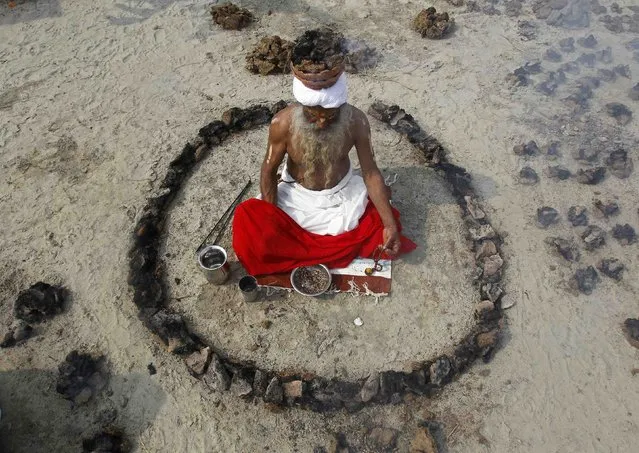 A Sadhu or a Hindu holy man offers prayers while sitting inside a circle of burning “Upale” (or dried cow dung cakes) on the occasion to mark the Basant or spring festival, on the banks of river Ganga in the northern Indian city of Allahabad January 24, 2015. Basant is celebrated mainly in the northern Indian states marking the start of the spring season. (Photo by Jitendra Prakash/Reuters)