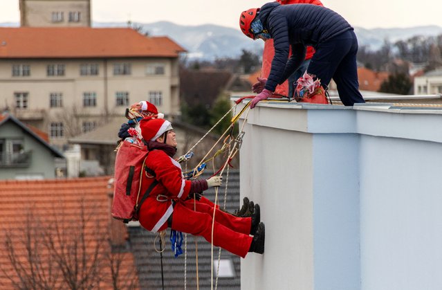 Volunteers dressed in Santa Claus costumes rappel from the roof of Children's Hospital Srebrnjak to bring gifts to the children, in Zagreb, Croatia on December 23, 2024. (Photo by Antonio Bronic/Reuters)