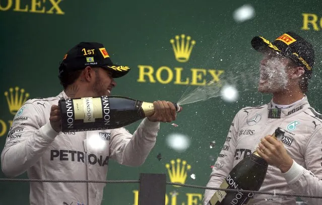 Formula One, F1, Brazilian Grand Prix, Circuit of Interlagos, Sao Paulo, Brazil on November 13, 2016. Race winning Mercedes' driver Lewis Hamilton of Britain (L) and teammate and second placed finisher Nico Rosberg of Germany spray champagne during the victory ceremony after the race. (Photo by Paulo Whitaker/Reuters)