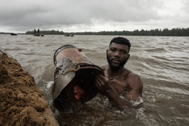 Cameroon, 2017. Sand diver, Simon. Simon was the strongest diver on this section of river. A former boxer he was a self-made man. Working his way up to buy his first pirogue, and then a second and then a third and finally a fourth. Simon harboured ambitions to move abroad and to start a new life. On average each diver retrieved around 1.7 tonnes of brickies sand in a roughly three hour shift. Incredible given that each bucket held around 15 kilos of sand. (Photo by Hugh Brown/South West News Service)