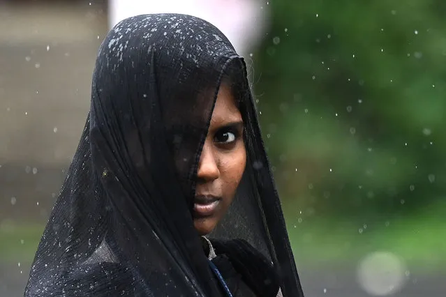 A woman looks on as she walks amid rainfall in Chennai on July 25, 2023. (Photo by R.Satish Babu/AFP Photo)