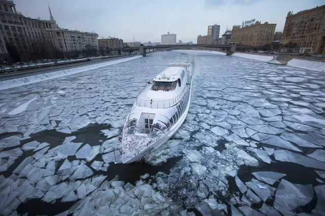 A tourist boat with restaurant aboard, especially designed for winter rivers, cruises the frozen Moskva River in Moscow, Russia, Monday, January 4, 2016. Temperatures dipped to -18 C (-0,4 F) in Moscow and -20  C (-4 F) in surrounding regions. (Photo by Alexander Zemlianichenko/AP Photo)