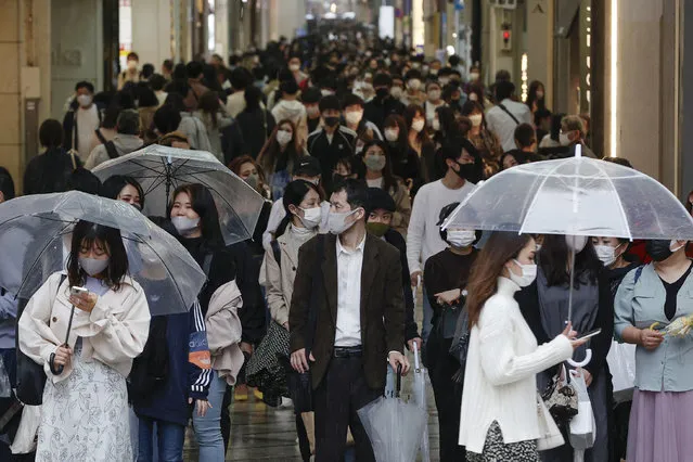 People wearing face masks to help curb the spread of the coronavirus walk in Osaka, western Japan, Monday, April 5, 2021. Semi-emergency coronavirus measures began in Osaka and its neighboring prefecture in western Japan and another prefecture in the north Monday as Japan tries to minimize the economic impact to specific areas where infections are rising back less than four months before the Tokyo Olympics. (Photo by Kyodo News via AP Photo)