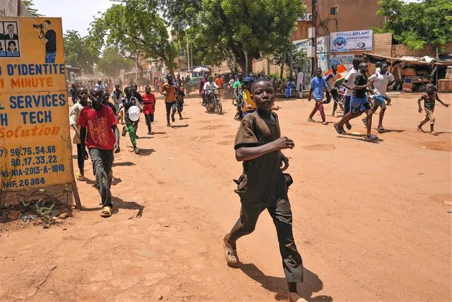 Children run in the streets of Niamey, Niger, Sunday, August 13, 2023. People marched, biked and drove through downtown Niamey, chanting “down with France” and expressing anger at ECOWAS. (Photo by Sam Mednick/AP Photo)