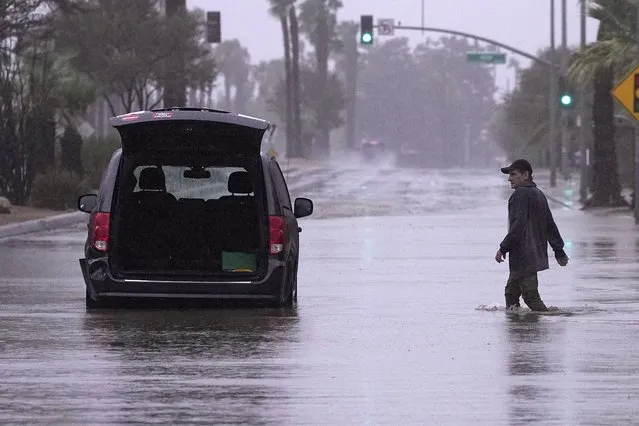 A motorist walks out to remove belongings from his vehicle after becoming stuck in a flooded street, Sunday, August 20, 2023, in Palm Desert, Calif. Forecasters said Tropical Storm Hilary was the first tropical storm to hit Southern California in 84 years, bringing the potential for flash floods, mudslides, isolated tornadoes, high winds and power outages. (Photo by Mark J. Terrill/AP Photo)