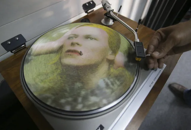 Rene Rivo, a Filipino David Bowie fan, plays a picture disc of Bowie's Hunky Dory on a turntable at his shop in suburban Paranaque, south of Manila, Philippines Tuesday, January 12, 2016. Bowie, the chameleon-like star who transformed the sound - and the look - of rock with his audacious creativity and his sexually ambiguous makeup and costumes, died of cancer Sunday, Jan. 10. (Photo by Aaron Favila/AP Photo)
