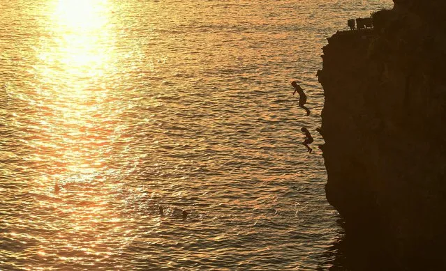 People dive into water near the Rocher de La Vierge in Biarritz, southwestern France, on August 23, 2023, as the heatwave sweeps across France. Temperatures in France hit an all-time high for late summer on August 23, 2023, the weather authority said, as the country continues to swelter under a punishing heatwave. (Photo by Gaizka Iroz/AFP Photo)