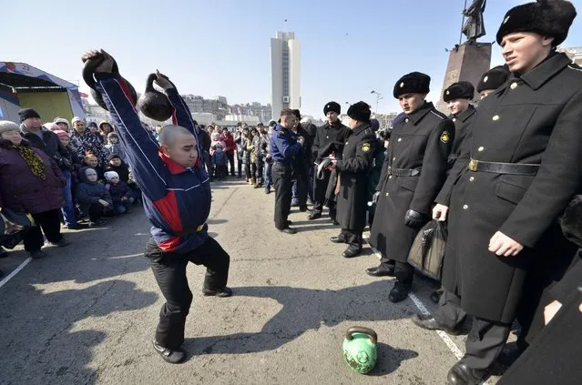 A Russian navy sailor lifts a weight while participating in a competition during celebrations for the Defender of the Fatherland Day in the far eastern city of Vladivostok February 23, 2015. (Photo by Yuri Maltsev/Reuters)