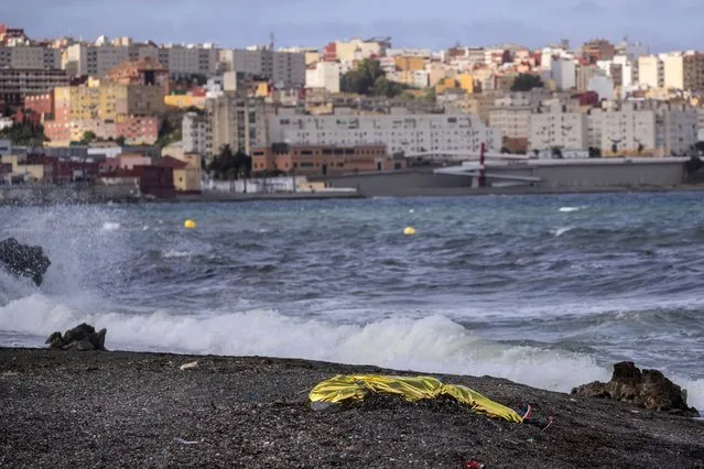 The body of a young man covered with an emergency blanket after being recovered by Spanish police from waters near the border between Morocco and Spain's north African enclave of Ceuta, Thursday, May 20, 2021. Spain says it has returned to Morocco over 6,600 of the more than 8,000 migrants who swam or jumped over border fences into one of Spain's enclaves in North Africa this week. Social services in Ceuta were dealing with thousands of calls from Moroccan parents looking for their children and trying to speed up family reunions, said authorities in Spain's north African enclave at the heart of a sudden humanitarian crisis and a diplomatic storm with Morocco. (Photo by Bernat Armangue/AP Photo)