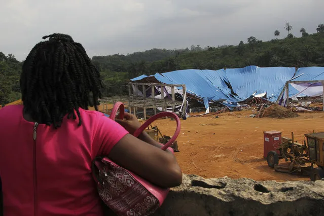 A woman stands to look at the site of a collapsed church in Uyo, Nigeria, Sunday, December 11, 2016.  Metal girders and the roof of a crowded church collapsed onto worshippers, Saturday, killing at least 160 people with the toll likely to rise, a hospital director said Sunday. (Photo by AP Photo)