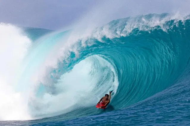 A surfer rides a wave as a big swell hits Teahupoo, Tahiti on April 30, 2023. (Photo by Brian Bielmann/AFP Photo)