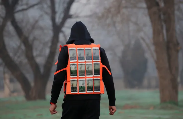 Artist Liu Bolin wearing a vest with 24 mobile phones walks in smog as he live broadcasts air pollution in the city on the fourth day after a red alert was issued for heavy air pollution in Beijing, China, December 19, 2016. (Photo by Jason Lee/Reuters)