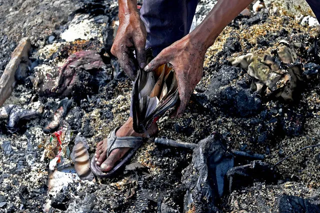 A Rohingya refugee looks for his belongings amid the charred remains of their camp following a fire incident that broke out earlier today in New Delhi on June 13, 2021. (Photo by Money Sharma/AFP Photo)