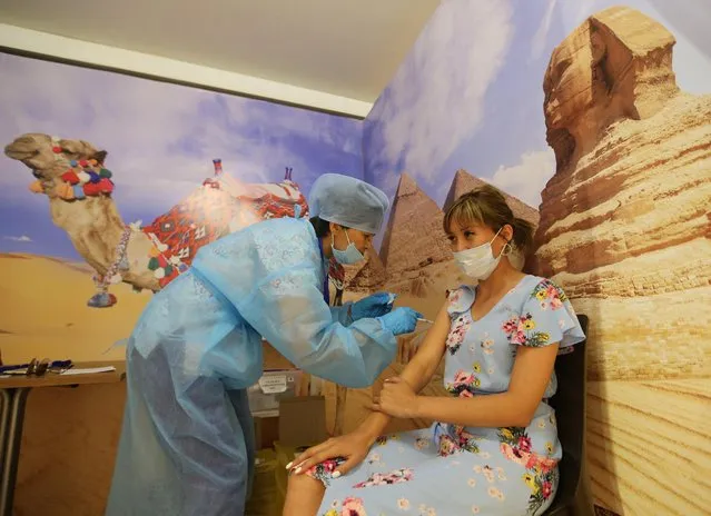 A woman receives a dose of Sputnik V (Gam-COVID-Vac) vaccine against the coronavirus disease (COVID-19) at a temporary vaccination unit set up at a former TikTok studio in the MEGA Park mall in Almaty, Kazakhstan on June 23, 2021. (Photo by Pavel Mikheyev/Reuters)