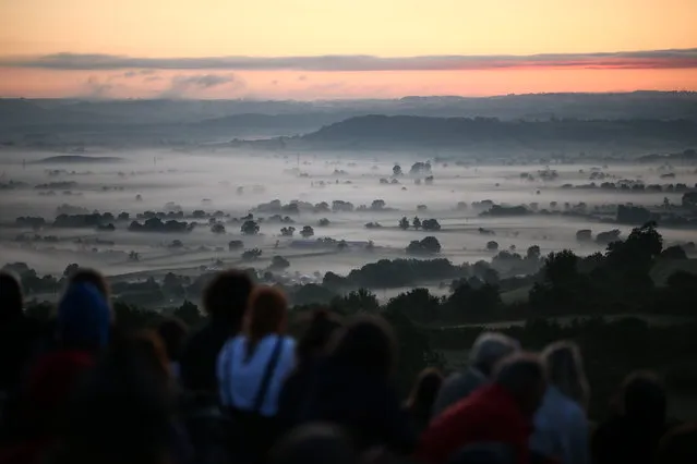 People wait for the sun to rise to make the Summer Solstice at Glastonbury Tor in Glastonbury, Britain, 21 June 2023. Each year people gather at the site, believed by some to be the Avalon of Arthurian legend, to celebrate sunrise on the longest day in the Northern hemisphere. (Photo by Adam Vaughan/EPA)
