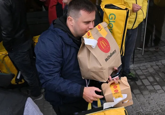 A delivery employee carries orders at a McDonald restaurant in Kyiv on September 20, 2022 as the US fast-food giant starts to reopen in the Ukrainian capital amid the Russian invasion of Ukraine. (Photo by Sergei Supinsky/AFP Photo)