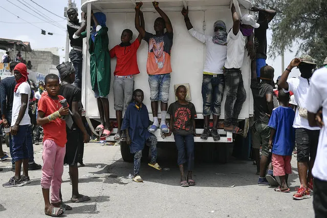 Youths and members of the gang led by Jimmy Cherizier, alias Barbecue, a former police officer who heads a gang coalition known as “G9 Family and Allies”, hang out during a march to demand justice for slain Haitian President Jovenel Moise, in the La Saline neighborhood of Port-au-Prince, Haiti, Monday, July 26, 2021. (Photo by Matias Delacroix/AP Photo)