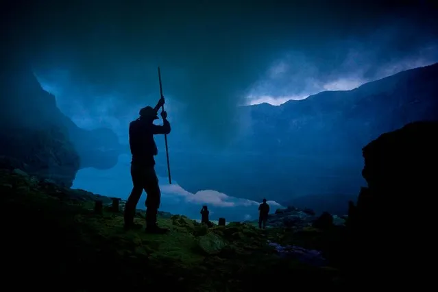 A miner uses a pole to extract sulphur from a pipe at the flow crater during the annual offering ceremony on the Ijen volcano. (Photo by Ulet Ifansasti/Getty Images)