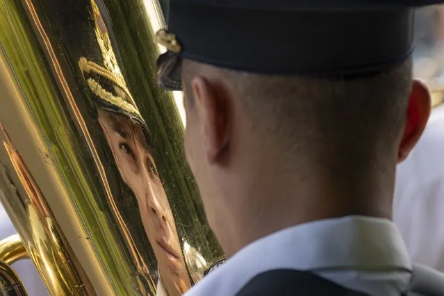 A member of a military band is reflected in a brass instrument during a ceremony for Aviation Day which celebrates aviators, military and civilian, who lost their lives in the line of duty or contributed to the evolution of Romanian aviation. in Bucharest, Romania, Tuesday, July 20, 2021. The traditional flyover by military aircraft was cancelled after a US Air Force Sikorsky UH-60 Black Hawk helicopter experienced technical issues and had to make an emergency landing on a busy boulevard last week while taking part in rehearsals for Aviation Day. (Photo by Vadim Ghirda/AP Photo)