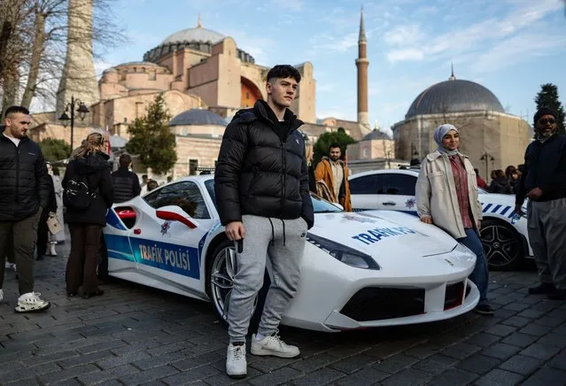 People take picture with the luxury Ferrari 488 GTB police car in front of the Hagia Sophia in Istanbul, Turkey, 31 December 2023. Turkish Interior Minister Ali Yerlikaya announced that Istanbul police have seized 23 luxury vehicles valued more than 3.5 million US dollars from criminal organizations and will keep them for their department's use. (Photo by Erdem Sahin/EPA)