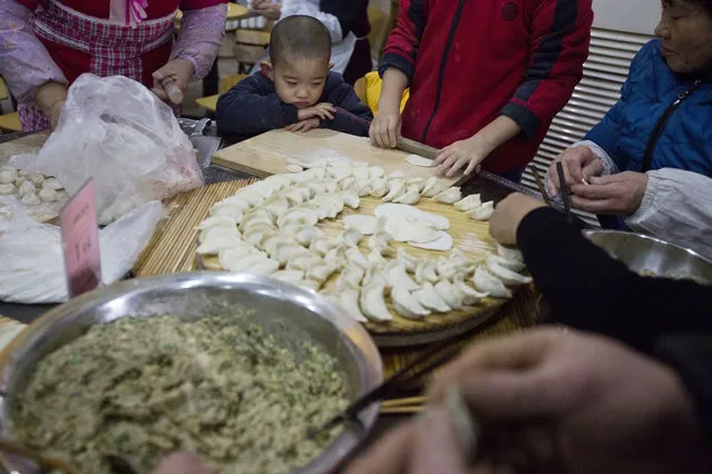 A child watches as adults make dumplings ahead of the Chinese lunar new year at a village on the outskirts of Beijing, China, Thursday, January 26, 2017. (Photo by Ng Han Guan/AP Photo)