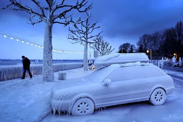 A man walks past an ice covered car on the frozen waterside promenade at Lake Geneva in the city Versoix, near Geneva on early February 5, 2012. (Photo by Fabrice Coffrini/AFP Photo)