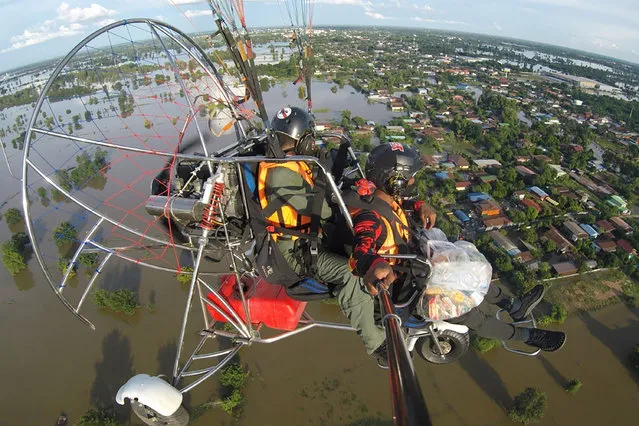 In this photo provided by Disaster Response Association of Phitsanulok, Thai paragliding team of Disaster Response Association of Phitsanulok fly while preparing to drop relief supplies over flood-hit villages in Sukhothai province, northern Thailand, Wednesday, September 29, 2021. According to the Department of Disaster Prevention and Mitigations on Thursday, Sept. 30, 2021, the flood has affected 227,470 households in 31 out of Thailand's 76 provinces. (Photo by Wichai Tiyasan/Disaster Response Association of Phitsanulok via AP Photo)