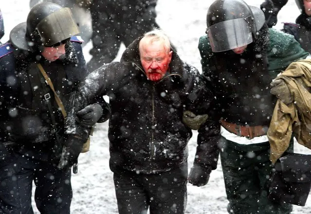 Ukrainian riot policemen detain a bleeding protester following clashes between security forces and pro-EU demonstrators in central Kiev on January 22, 2014. Five activists were killed and 300 wounded in the Ukrainian capital Kiev in a day of intense clashes with security forces, the medical centre of the protest movement said. (Photo by Anatolii Boiko/AFP Photo)