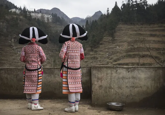Girls of the Long Horn Miao ethnic minority wear headdresses as they stand near their house after Tiaohua or Flower Festival as part of the Lunar New Year  on February 7, 2017 in Xiaobatian village, Guizhou province, southern China. The Long Horn Miao are recognized for their declining practice of wrapping a blend of linen, wool, and the hair of their ancestors around animal horns  or a wooden clip to make headdresses.  Many young women say they now wear the headdresses only for special occasions and festivals, as the ornaments, which are attached by the horns to their real hair, have proved impractical for modern daily life in a fast changing world. China officially recognizes 56 different ethnic minorities, and statistics show over 7 million Chinese identifying themselves as Miao. But the small Long Horn Miao community counts only around 5000 people living in 12 villages, whose age-old traditions, language, and culture are fading. It is increasingly difficult in a modernizing China, as young people are drawn from remote rural villages to opportunities in bigger cities amongst wide-scale urbanization. Farming and labour remain the mainstays of life for the Long Horn Miao, leaving the area relatively poor in comparison with many parts of China. The government has invested significant amounts into local infrastructure and the tourism industry to try to bolster the local economy. (Photo by Kevin Frayer/Getty Images)