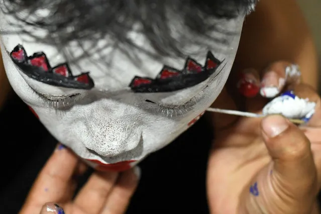 A boy gets his face painted before performing in a play during the Indra Jatra Hindu festival at Basantapur Durbar Square in Kathmandu on September 22, 2021. (Photo by Prakash Mathema/AFP Photo)