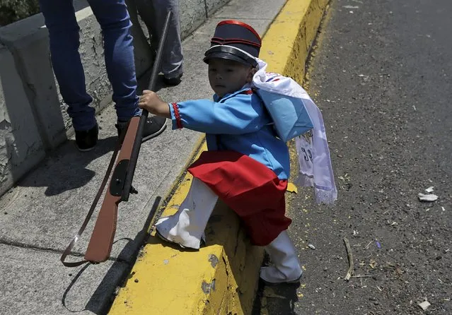 A Mexican child wearing period costume holds a homemade shotgun during the re-enactment of the battle of Puebla, along a street in Mexico City, May 5, 2015. (Photo by Henry Romero/Reuters)